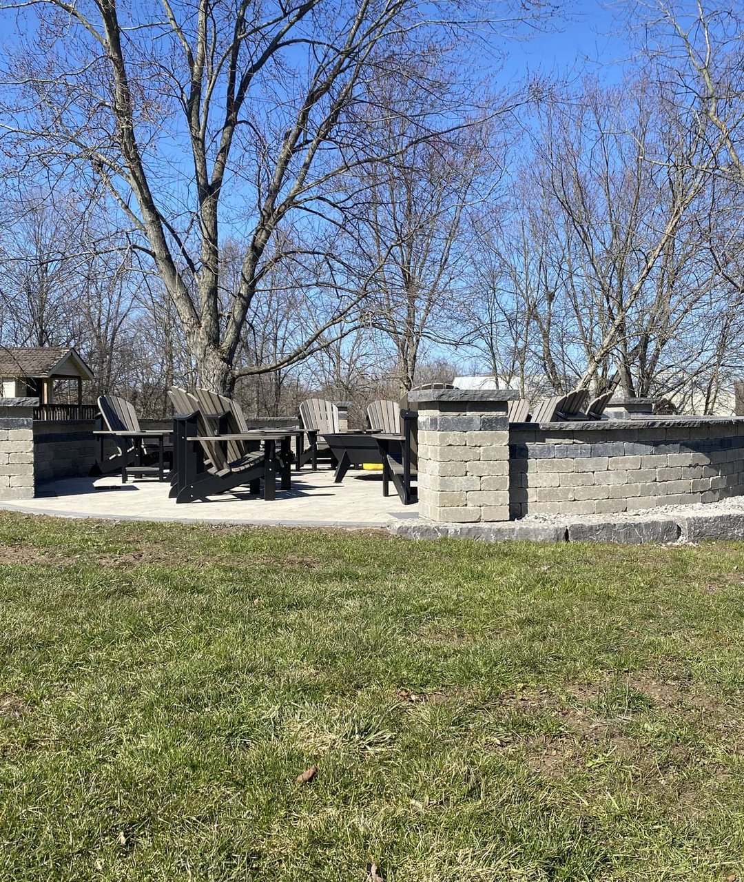 Curved stone seating wall surrounding a poured concrete fire pit pad in a backyard