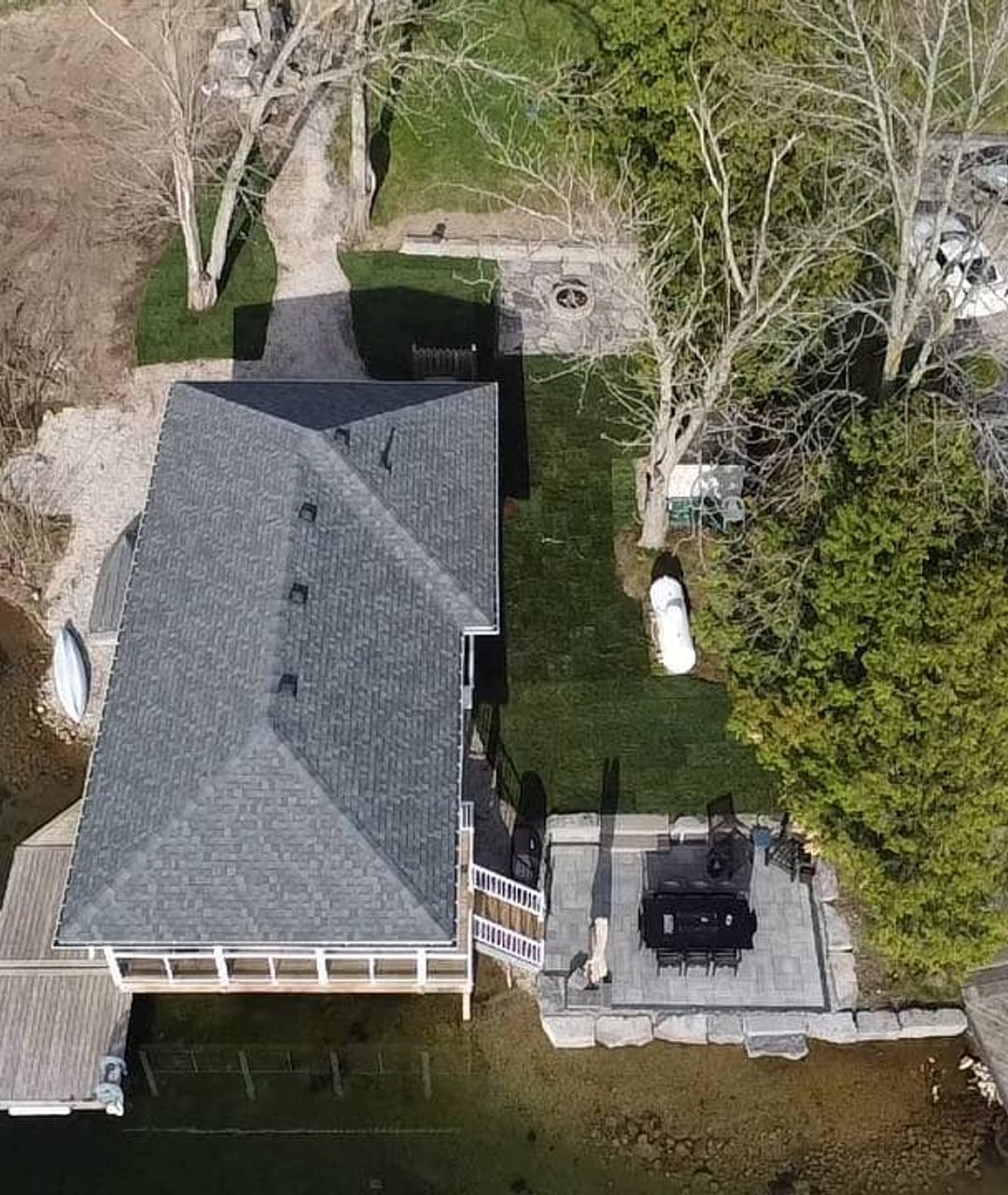 Aerial view of a lakefront home with a finished dock and patio installation