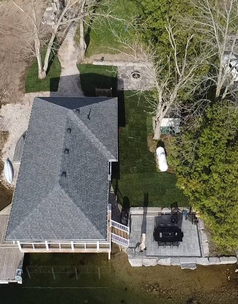 Aerial view of a lakefront home with a finished dock and patio installation