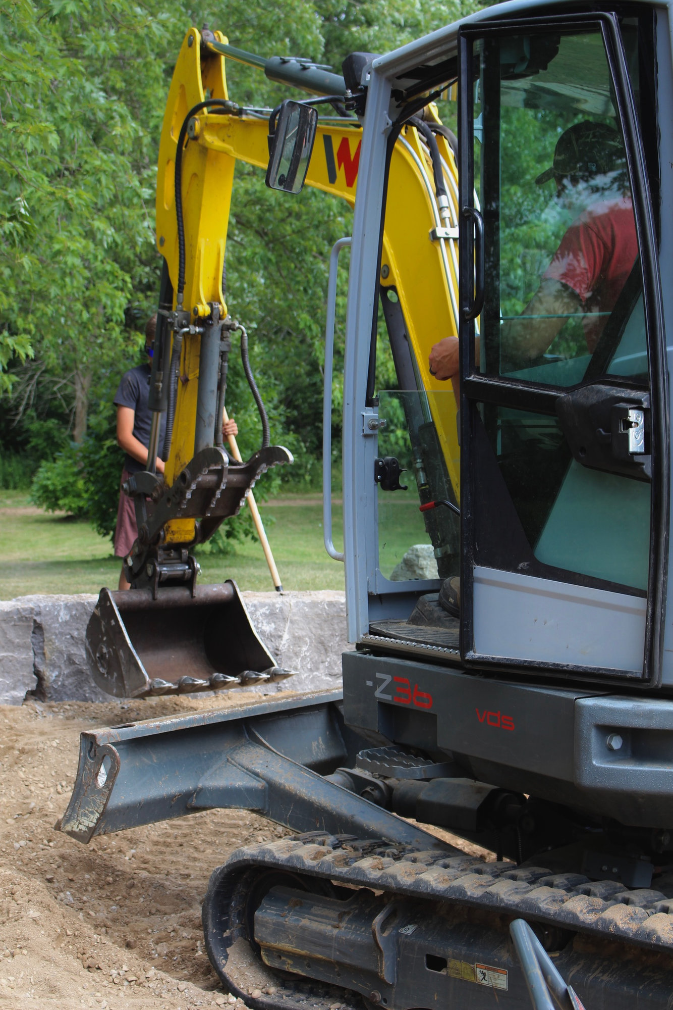 ExCL operator using a mini excavator to set armour stone blocks on site